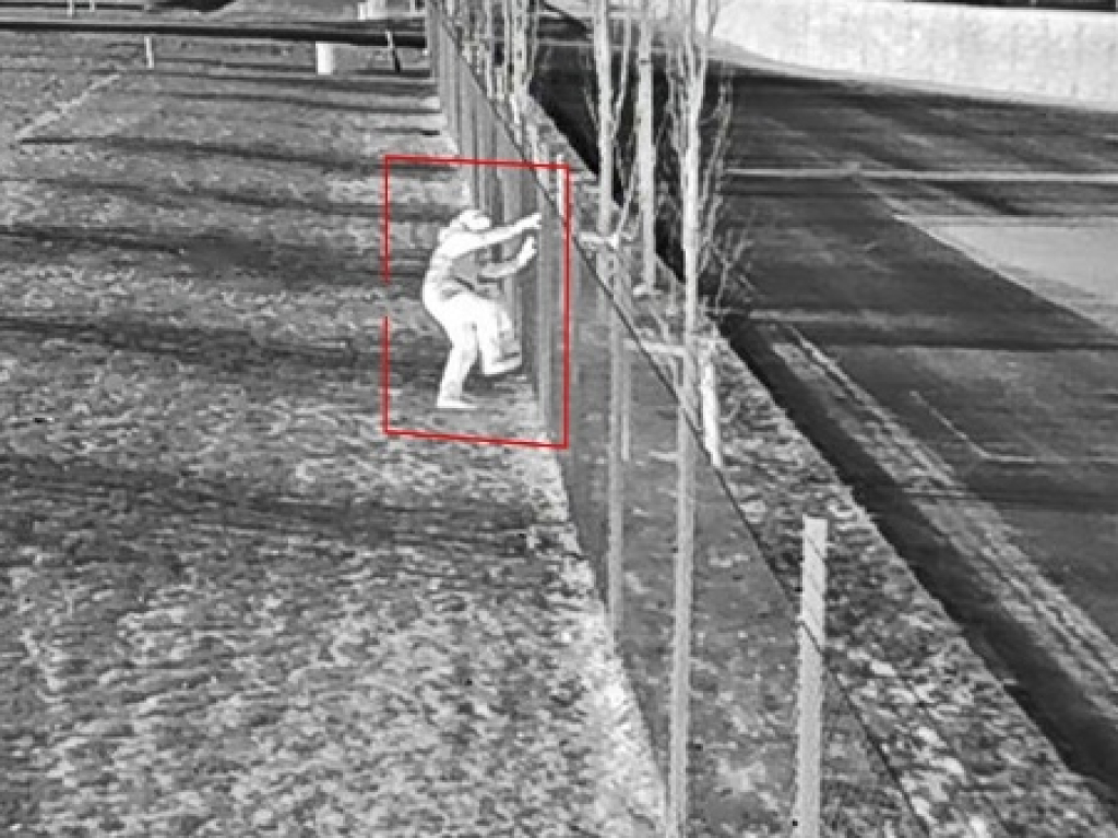 Thermal image of intruder climbing over fence